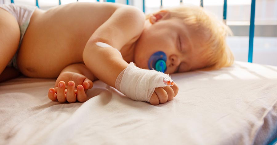 Baby asleep in hospital bed.