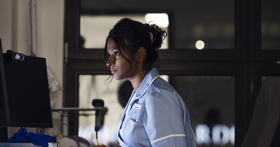 Nurse working at computer in darkened room