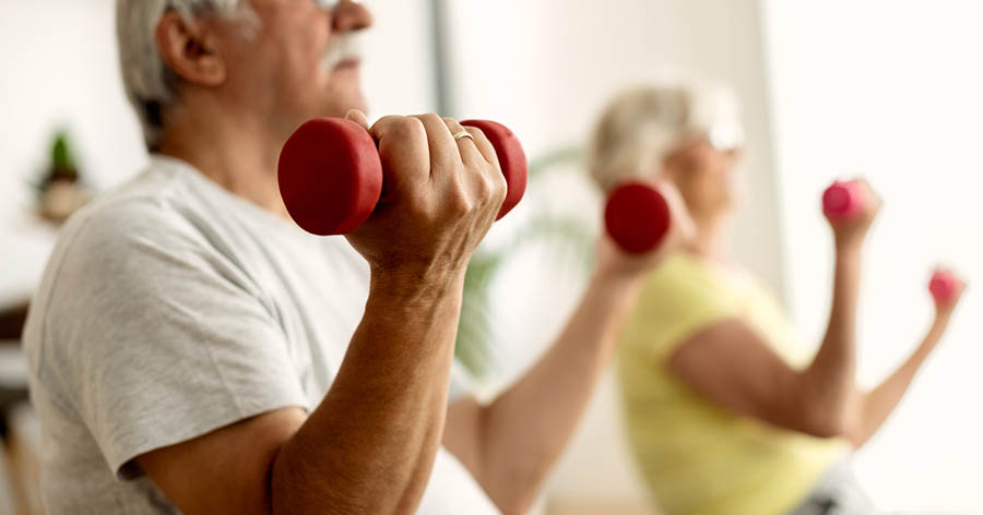 Two older people taking part in sitting exercise class.