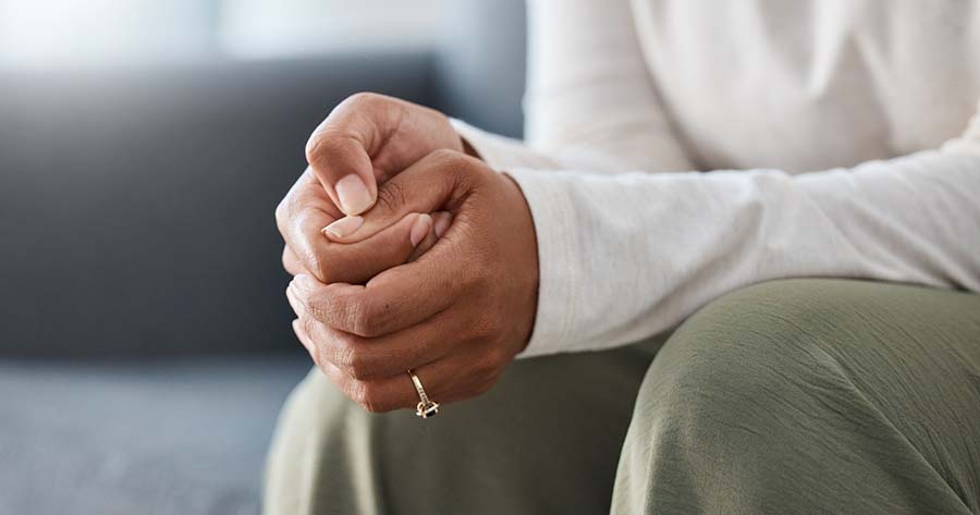 Woman sits anxiously with folded hands